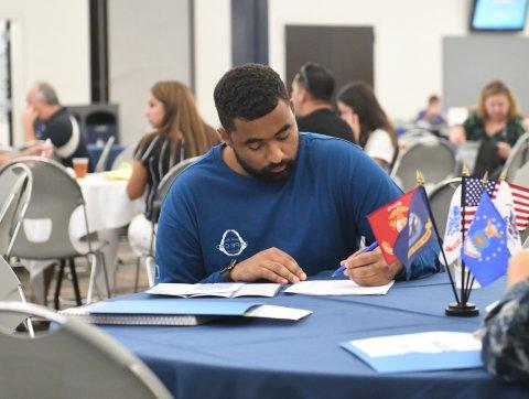 A veteran sits a table filling out his information for assistance.