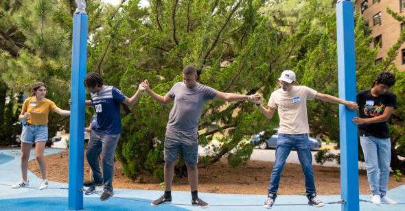 students holding hands while standing on rope 